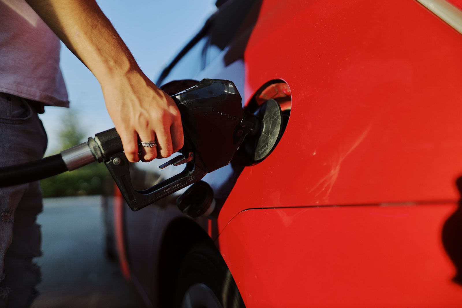 Fuel being poured into a car filler neck at the roadside after running out of gas