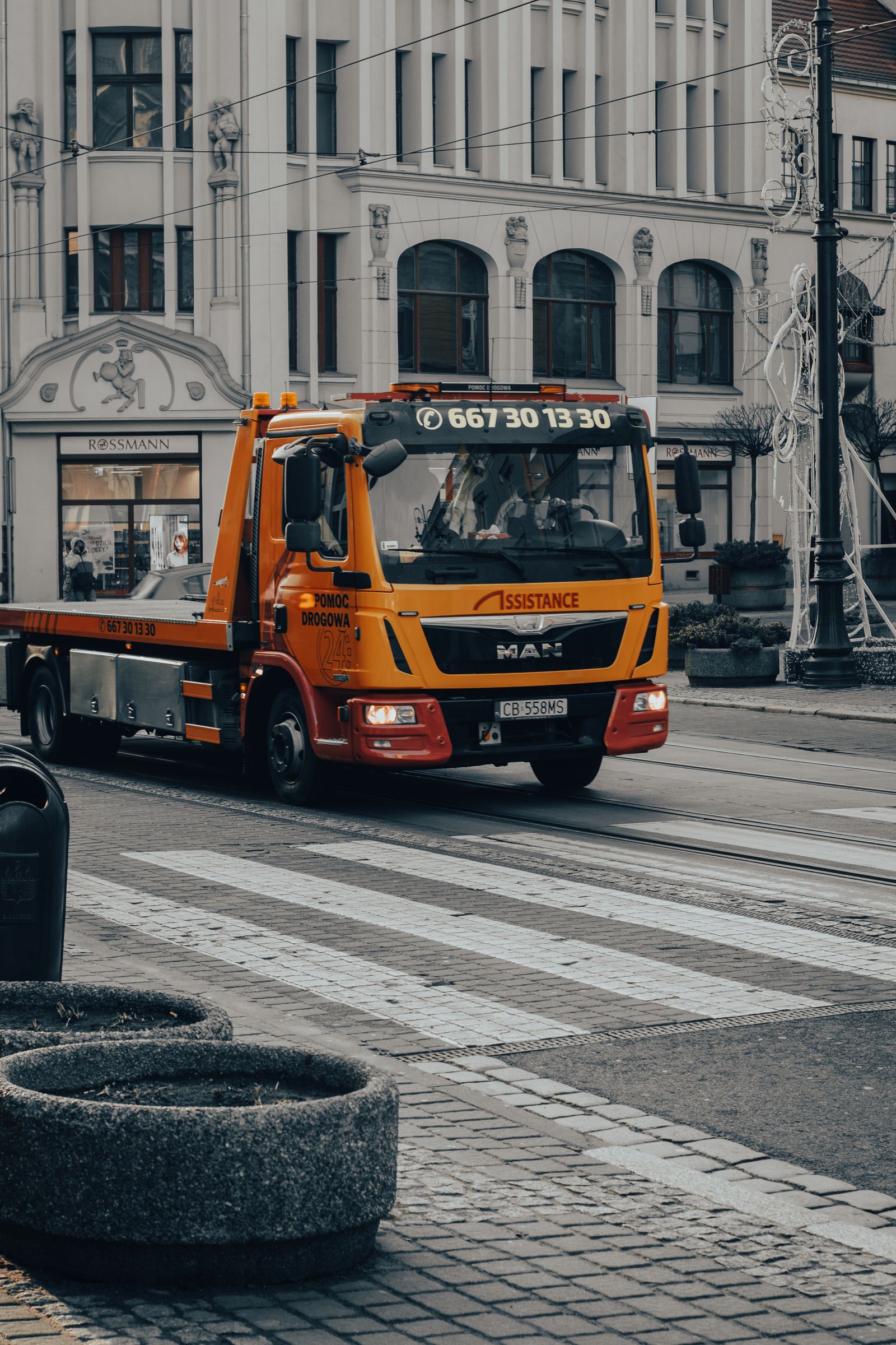 Yellow flatbed tow truck parked on a city street with its deck tilted ready to load